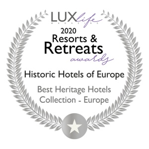 Un badge circulaire en argent avec une étoile en bas indique : "LUX Life Magazine 2020 Resorts & Retreats Awards. Hôtels historiques d'Europe. Meilleure collection d'hôtels du patrimoine - Europe.