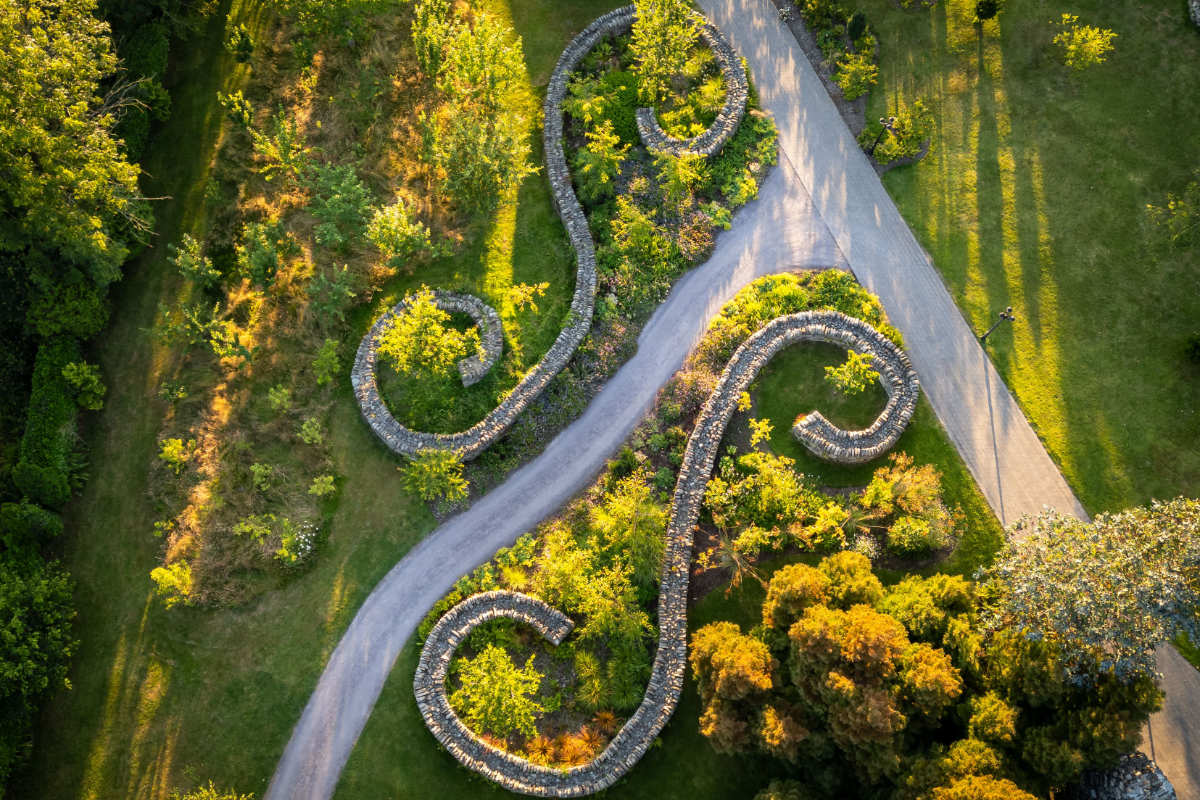 Veduta aerea di un sinuoso giardino di muri in pietra con sentieri e vegetazione, che formano modelli curvi simmetrici all'interno di un parco paesaggistico in un incantevole hotel di campagna in Irlanda.