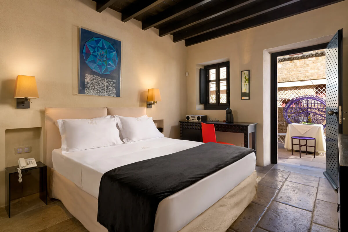 A bed in an Allegory Boutique Hotel Suite, with a terrace on Rhodes Island.