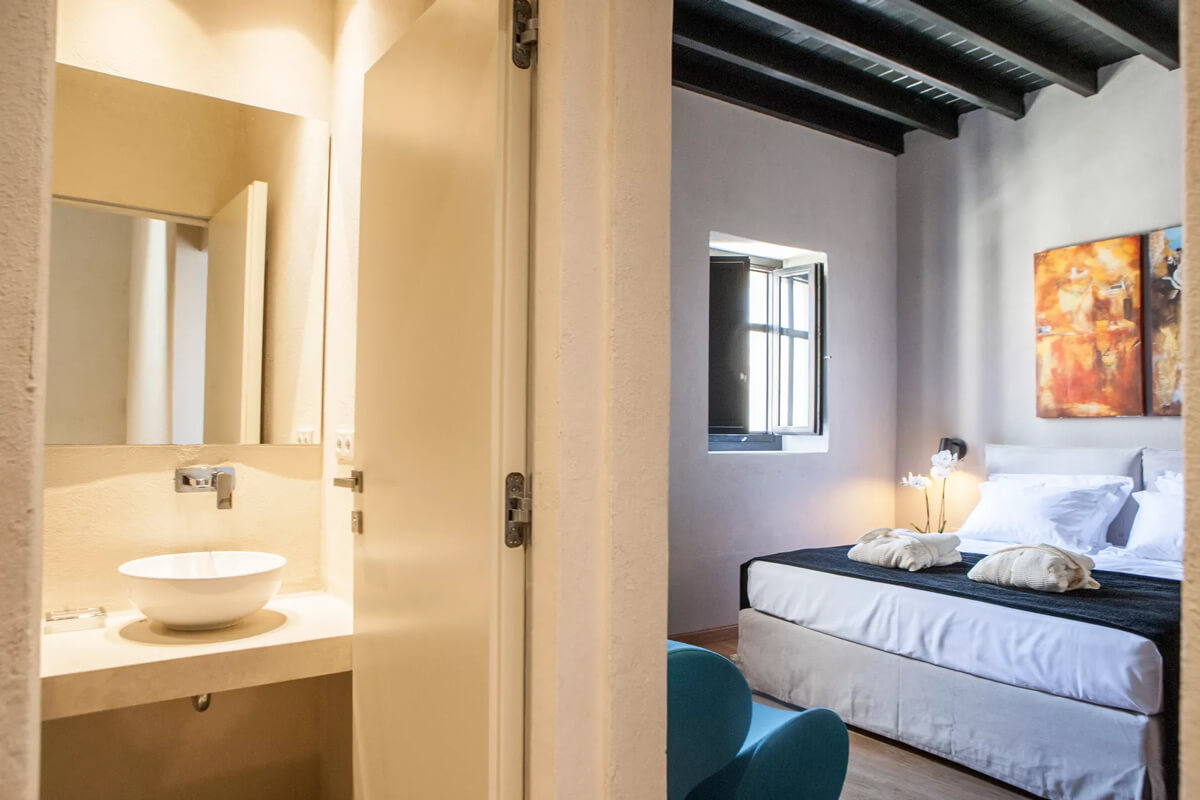A suite in the Allegory Boutique Hotel in Rhodes, Greece, with a bed, a sink, and a painting.
