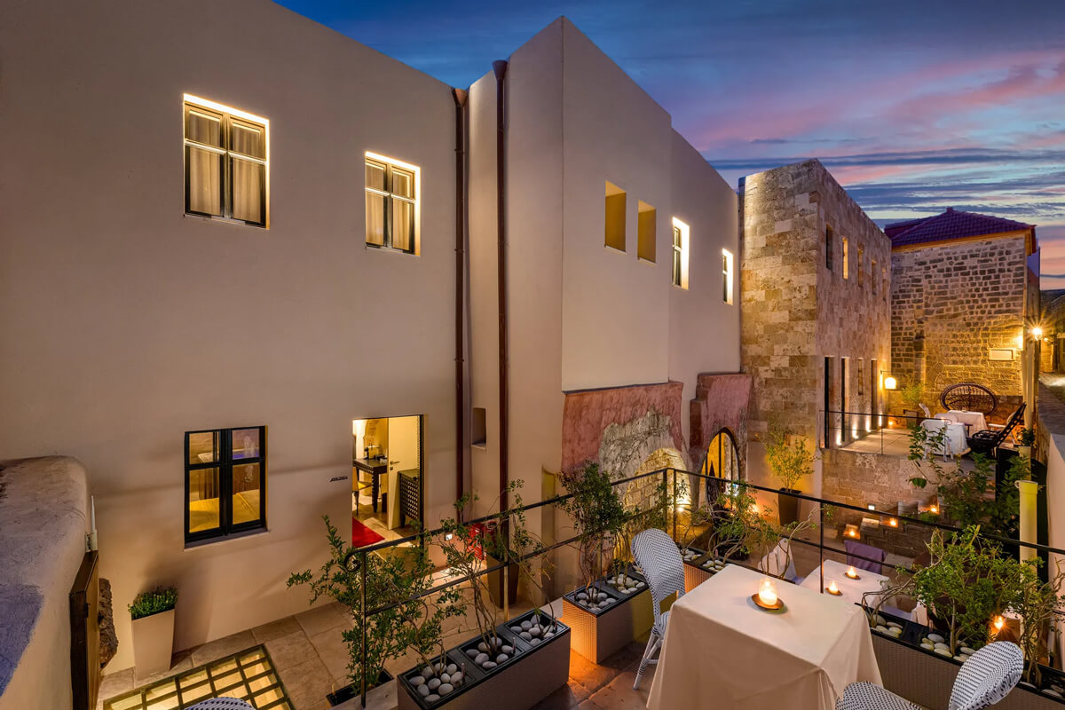The courtyard with tables and chairs at dusk at Allegory Boutique Hotel, Rhodes, Greece.