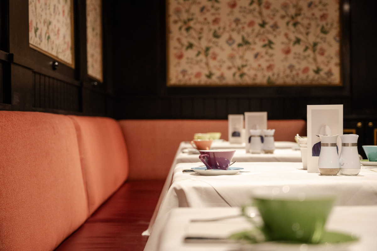 L'interno, che ricorda il fascino dell'Hotel Erzherzog Rainer, è caratterizzato da una lunga panca rossa imbottita lungo una parete ornata da carta da parati floreale, dove i tavoli sono apparecchiati con tazze e piattini colorati.