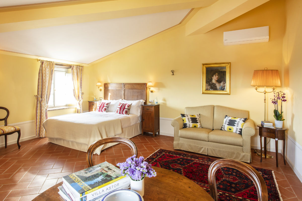 Experimente el encanto de la Toscana en esta espaciosa habitación adornada con azulejos de terracota. Con una cama de matrimonio, un acogedor sofá bajo un cuadro artístico y una mesa repleta de libros, esta habitación es un trozo de lujo que recuerda al Palazzo Tiglio. Disfrute de la luz natural que entra por la ventana.