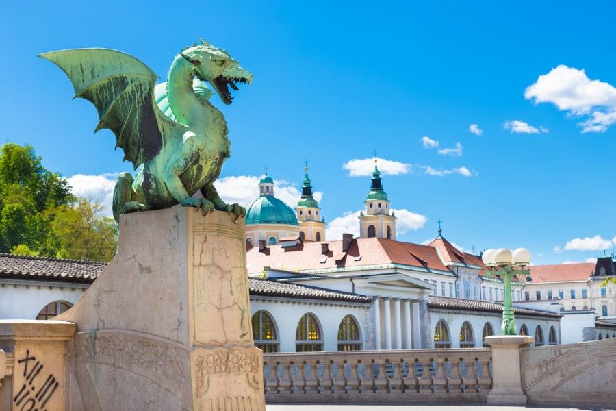 Bronze dragon sculpture overlooking historical buildings under a clear blue sky, one of the must-see things to do in Europe over Easter.