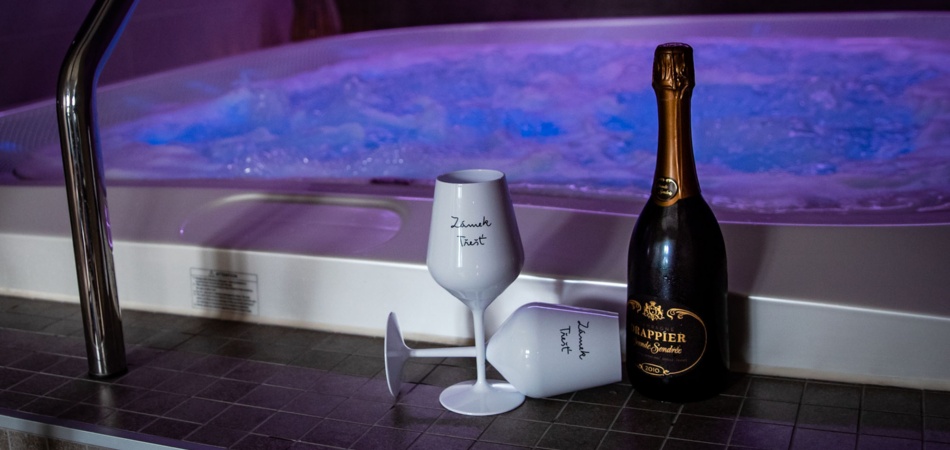 A bottle of wine and a bottle of champagne sitting next to a hot tub.