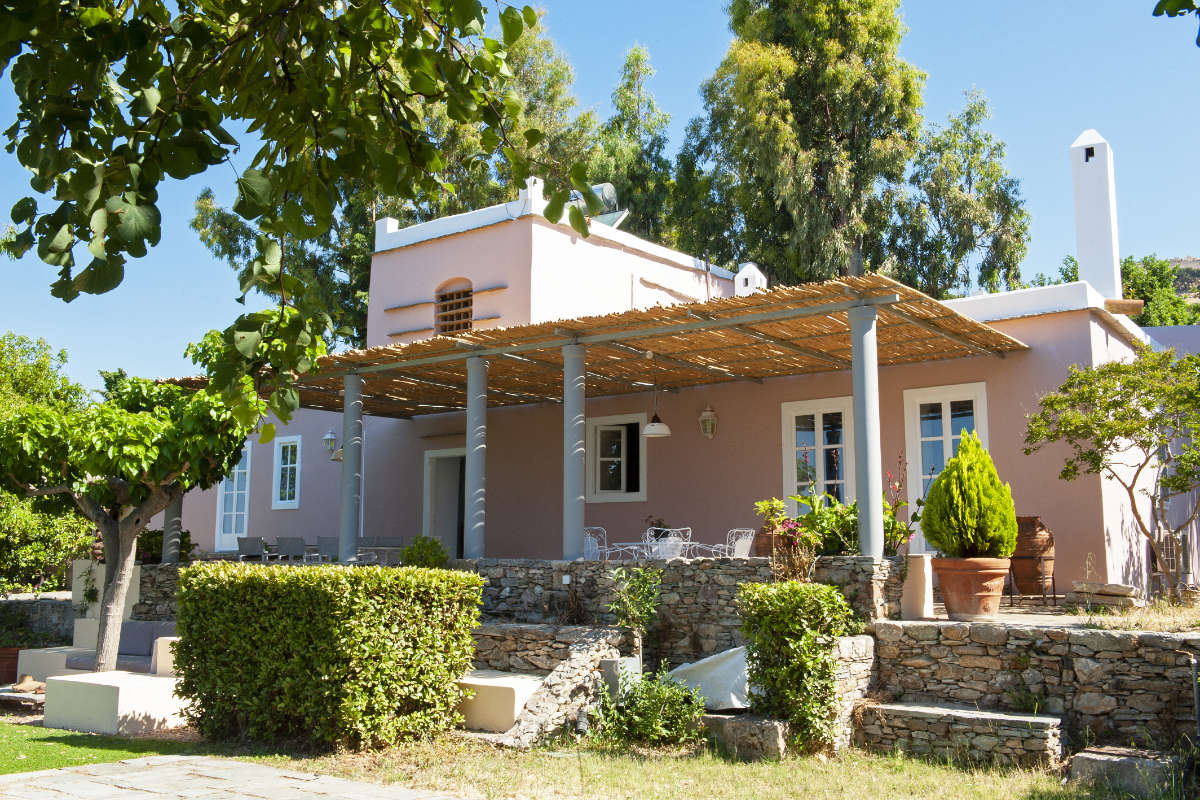 A house with a pergola and bushes.
