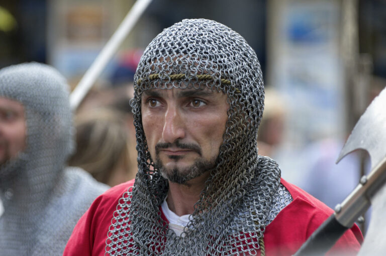 A man wearing a chainmail coif and a red tunic at the Medieval Rose Festival of Rhodes in Greece.