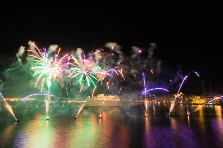 Colorful fireworks display over a night-time city waterfront during the International Fireworks Festival in Malta