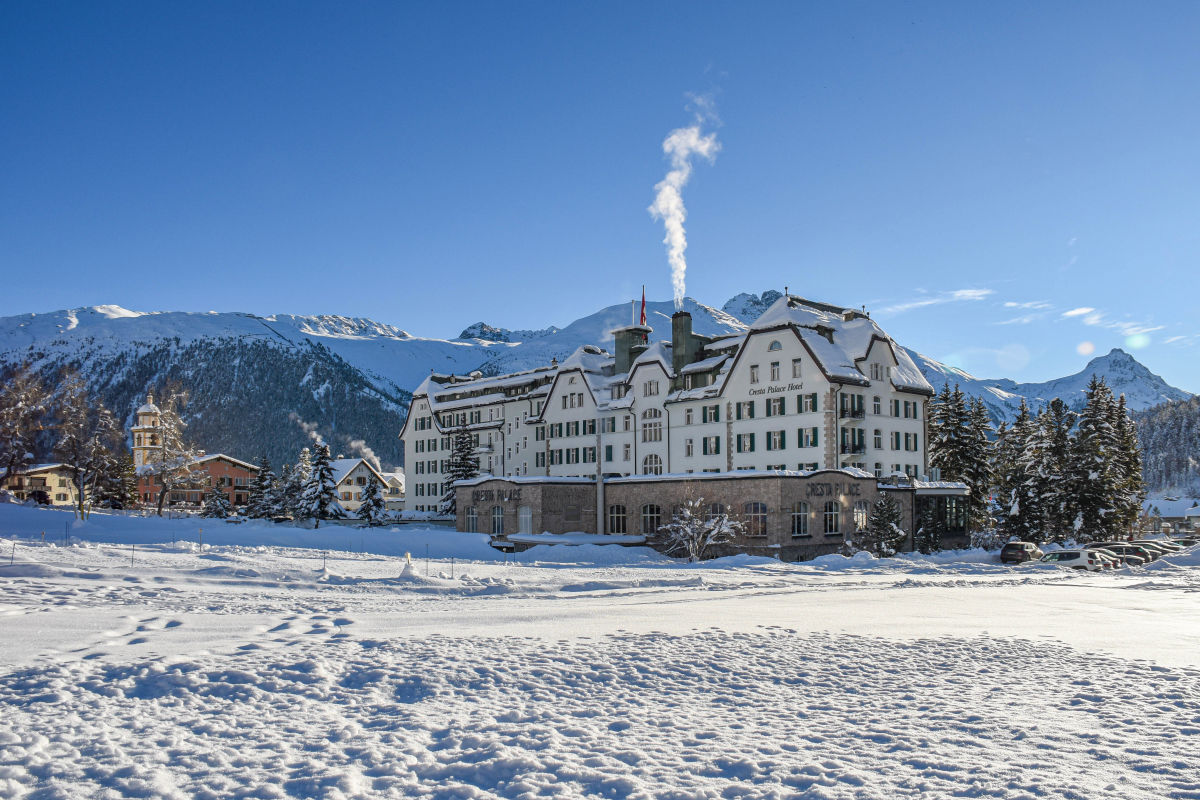 Vier-Sterne-Hotel Cresta Palace Celerina in einer verschneiten Landschaft mit Bergen im Hintergrund im Engadin, Schweiz.