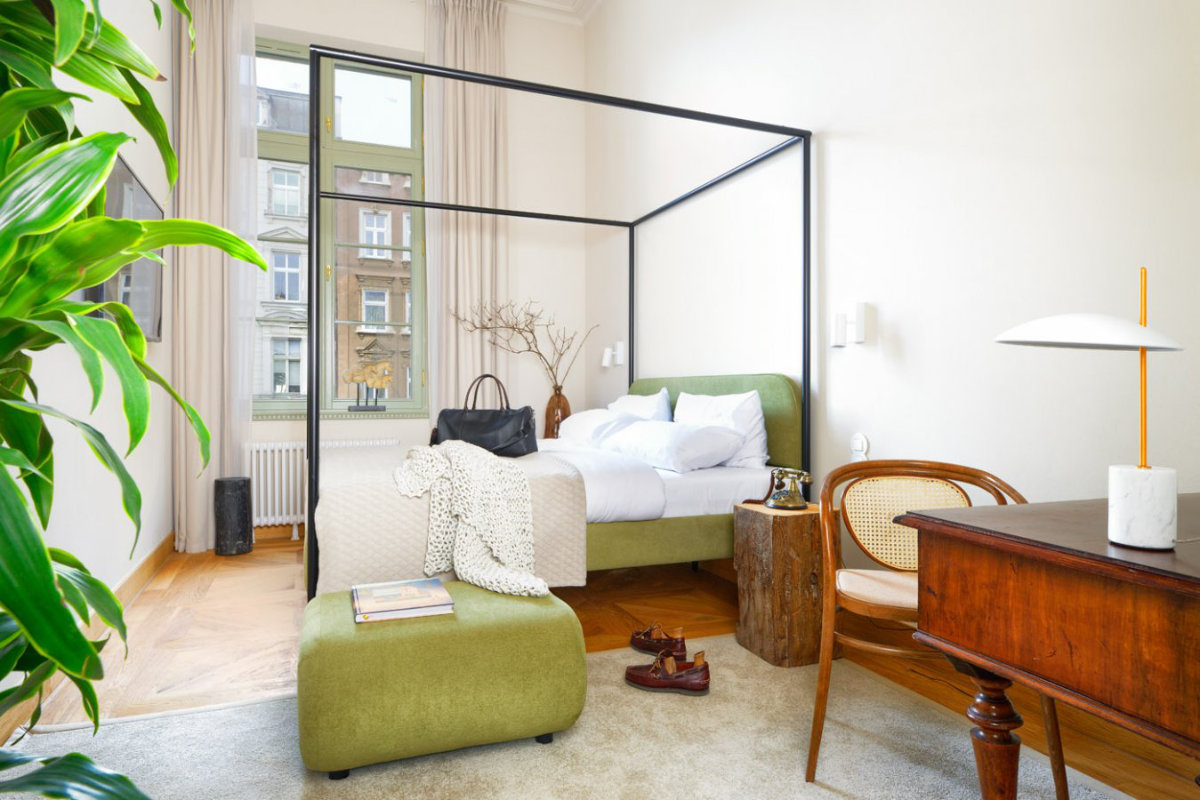 La luminosa camera da letto, che ricorda lo stile elegante di Dwór Uphagena, presenta un letto a baldacchino verde, una scrivania e una sedia in legno. Un'ampia finestra con tende ne esalta il fascino, mentre una pianta e oggetti decorativi creano un'atmosfera accogliente.
