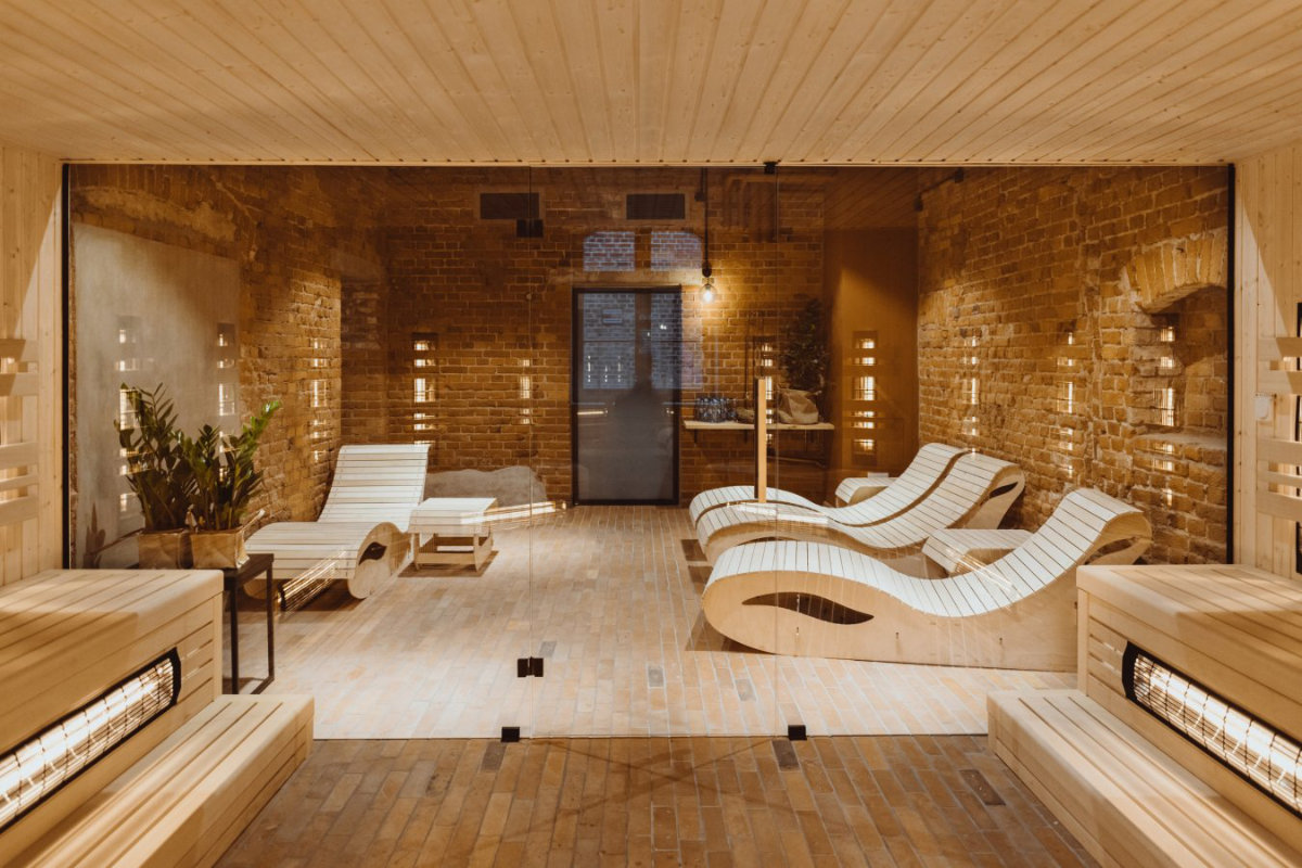 La moderna sala termale del Dwór Uphagena vanta pareti in mattoni ornate da sedie a sdraio in legno e illuminazione ambientale, creando un rifugio sereno.