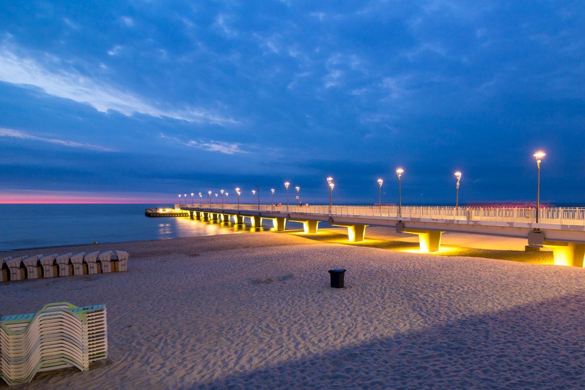 Un lungo molo illuminato si protende nel mare al tramonto a Kolobrzeg, in Polonia.
