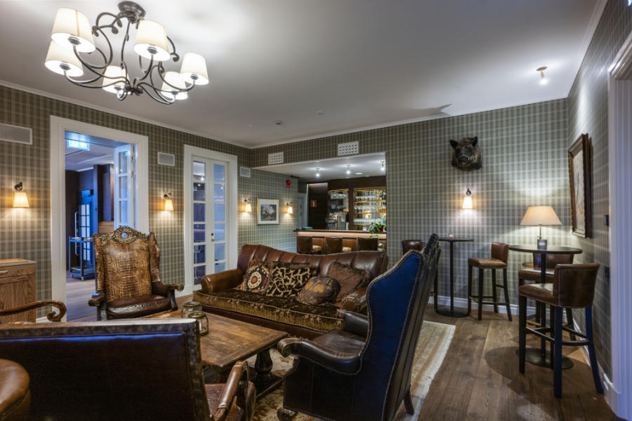 Eine gemütliche Lounge im Eriksberg Hotel mit Ledersofas und -sesseln, Holztischen, gemusterten Tapeten, Wandlampen und einem Barbereich im Hintergrund.