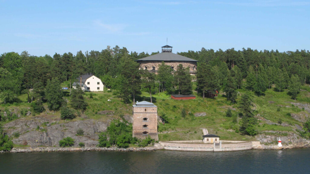 Le patrimoine entre ses mains : Les femmes qui ont façonné les hôtels historiques d'Europe 1 L'hôtel et la forteresse de Fredriksborg se trouvent au sommet d'une colline boisée au bord d'une rivière. Sa tour et ses bâtiments plus petits sont entourés d'arbres sous un ciel bleu clair, ce qui donne un aperçu pittoresque de l'histoire de l'hôtel en Suède.