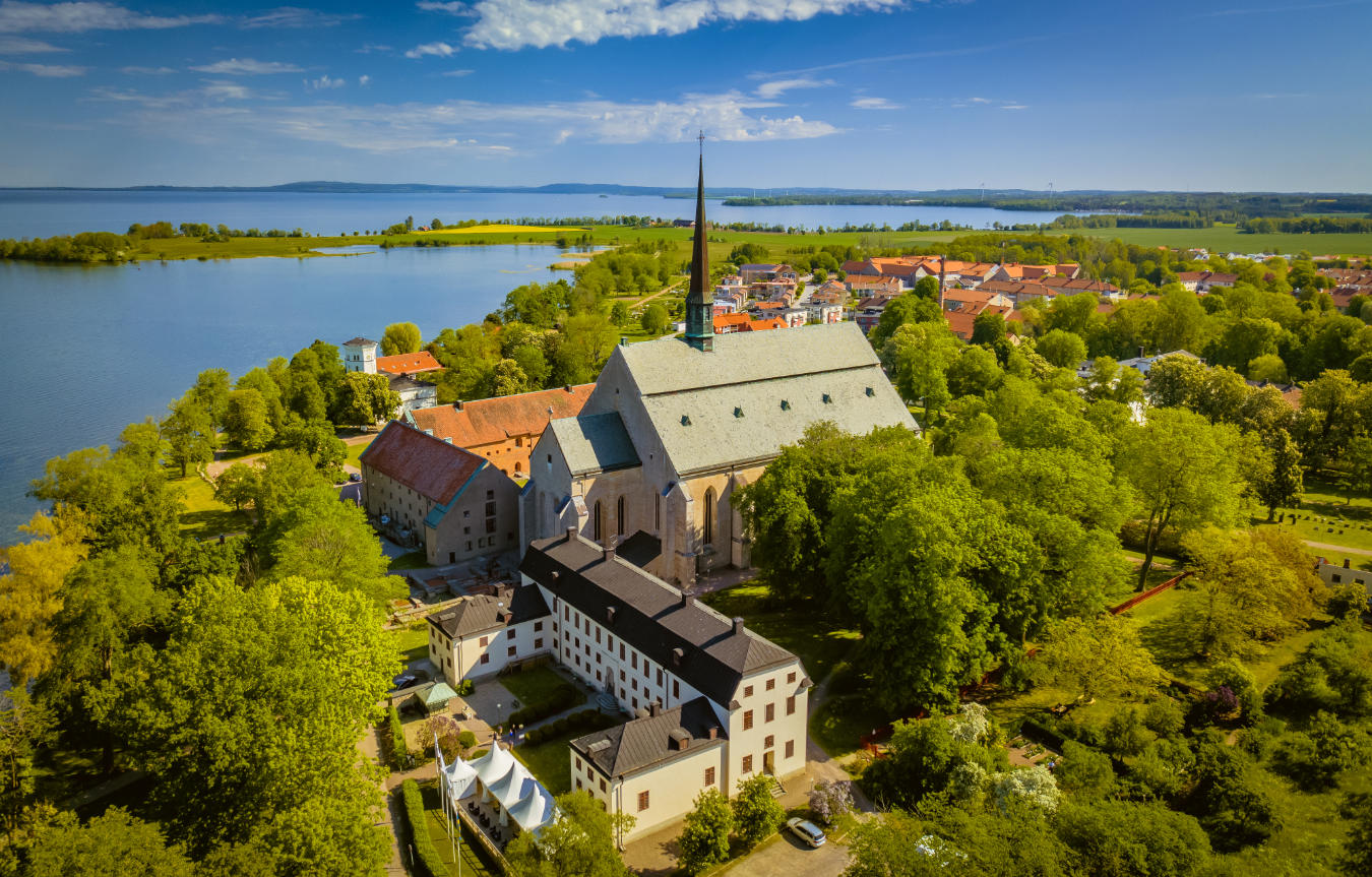 7 vacaciones en Europa que podrían cambiar su vida 7 Vista aérea de una gran iglesia histórica rodeada de árboles, edificios y el Vadstena Klosterhotel
