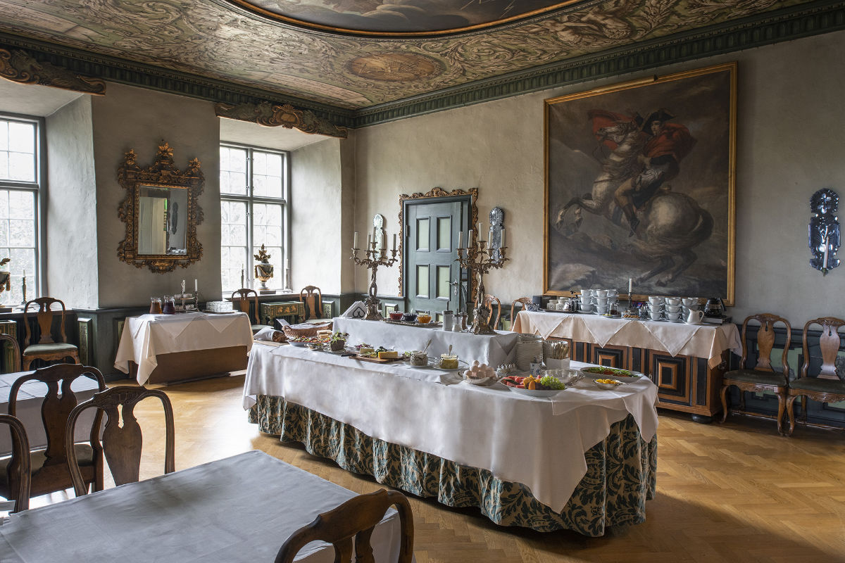 Västana Slott, Sweden, a historic dining room with ornate ceilings and a large painting, featuring buffet tables