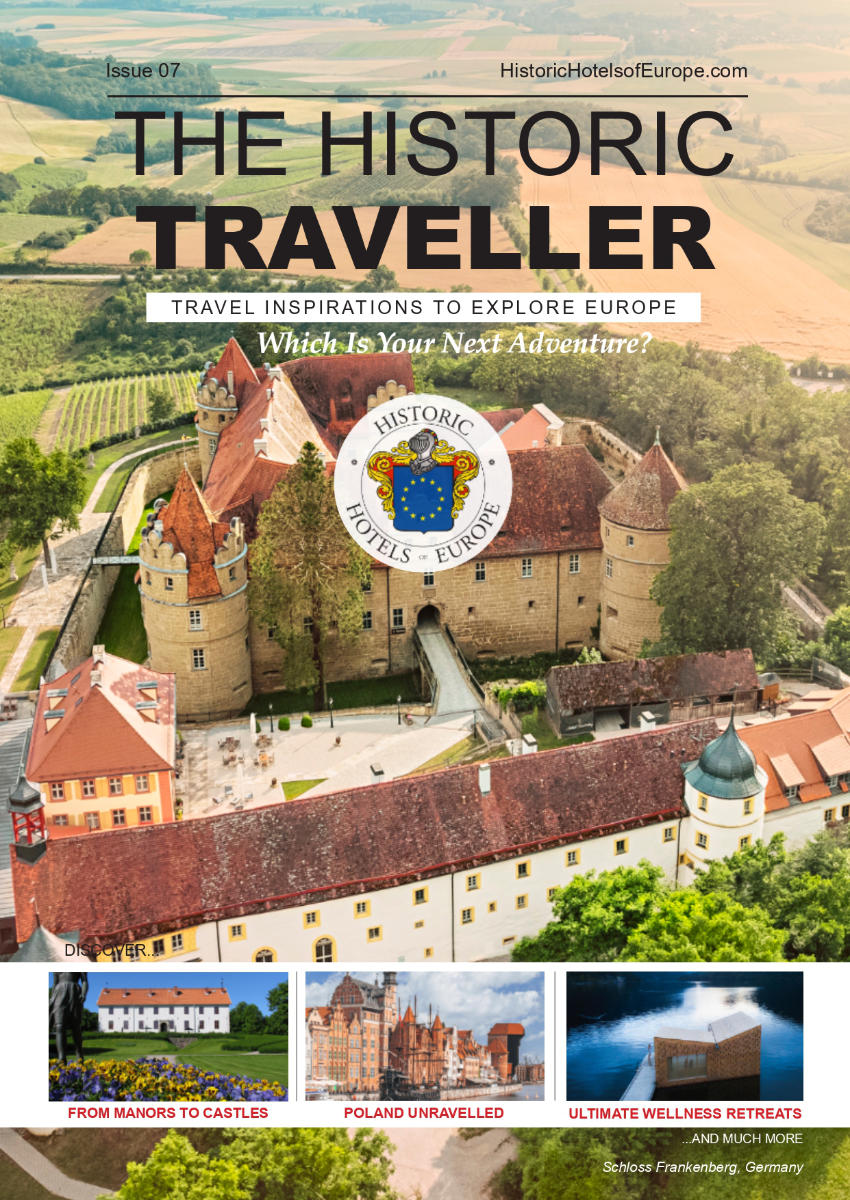 Aerial view of a historic castle surrounded by greenery, featured on the cover of "The Historic Traveller" magazine promoting travel in Europe.