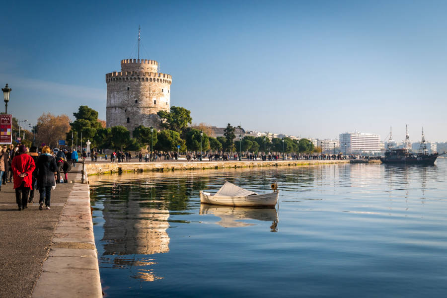 Europe’s Best-Kept Secrets: Lesser-Known Historic Hotel Escapes 4 The image shows the White Tower of Thessaloniki by the waterfront, inviting visitors to stroll along the promenade or discover Lesser-Known Historic Hotel Escapes nearby, as a small boat floats peacefully on the calm water.