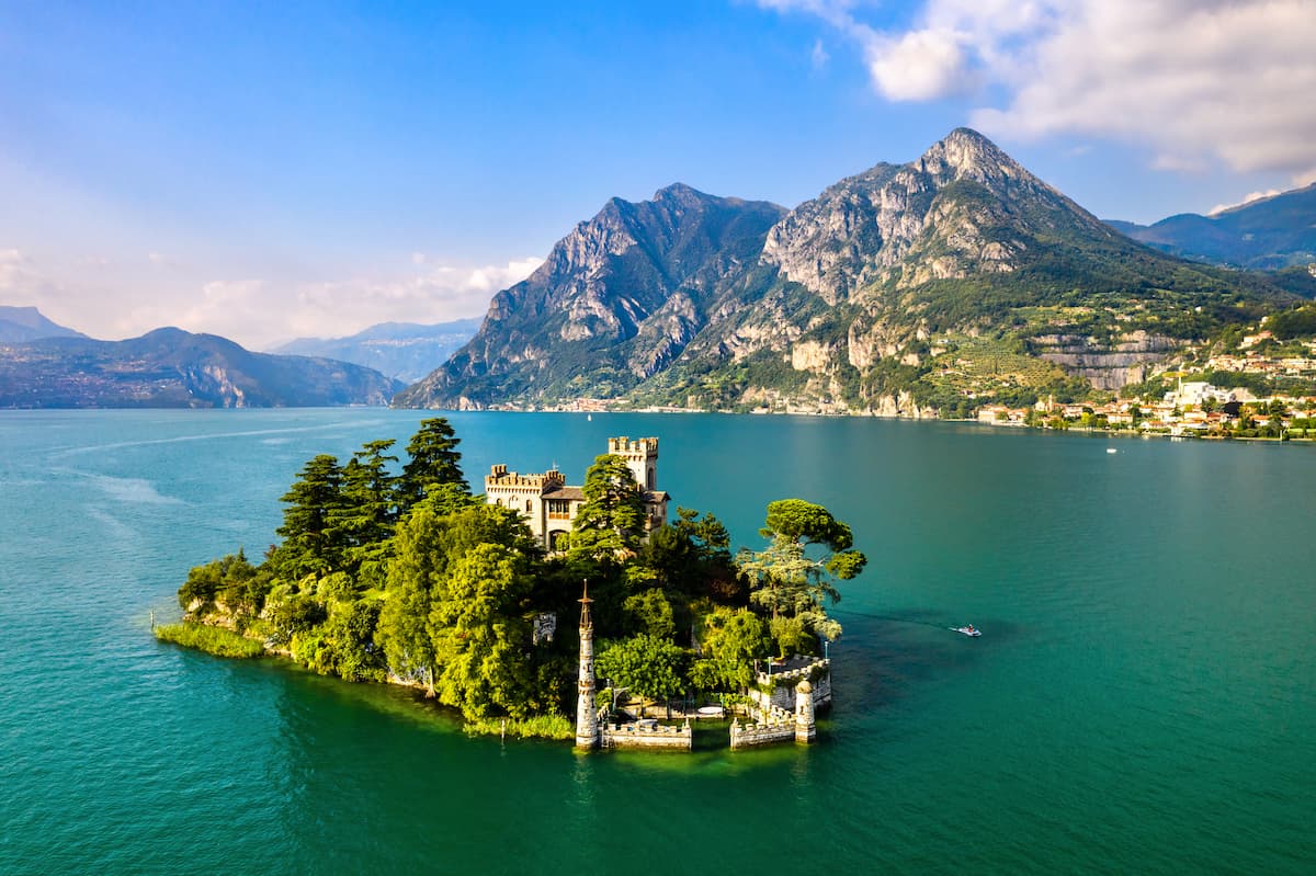 Esperienze 1 A villa on Loreto Island in Lake Iseo, a small, tree-covered island in a lake surrounded by mountains.